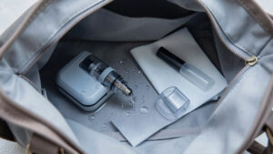 Cigarette électronique présentant une fuite dans un sac ouvert, accompagnée d’un étui protecteur et d’un chiffon absorbant.